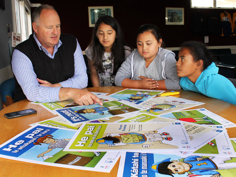 Principal Peter Barker shows the new posters to pupils Leah Walker, Jade Nelson and Crystal Mihaka-Barrett.