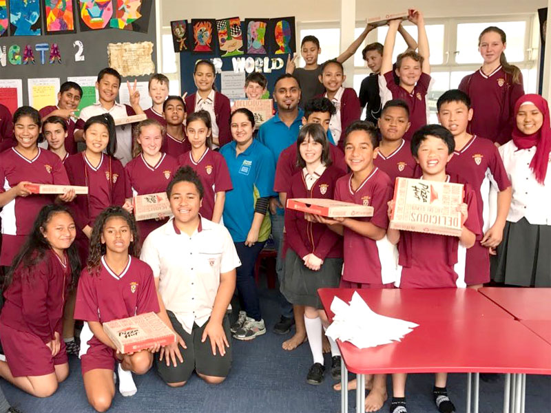 Ajneel and Bhartika Singh hand out pizza to Room 17 students at Howick intermediate School for winning the Cleanest Classroom Award.